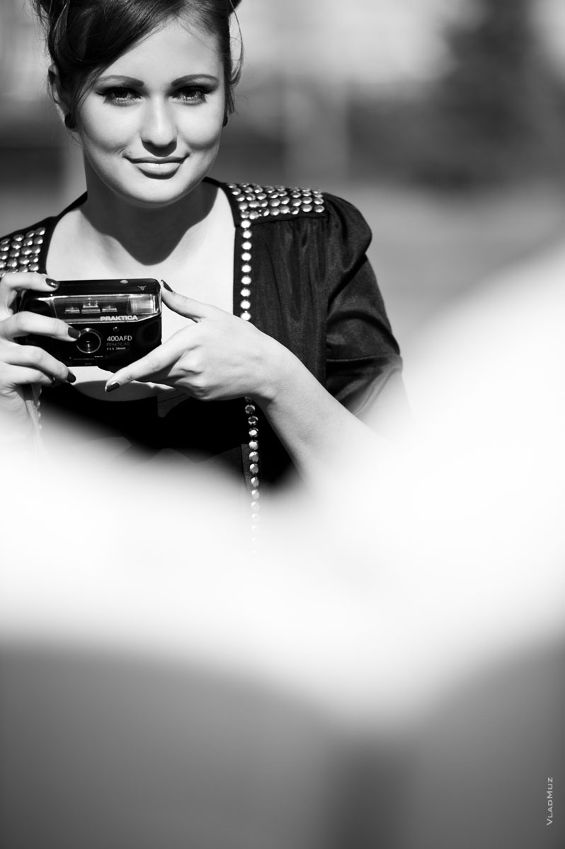 Черно-белый фотопортрет девушки с фотокамерой в руках