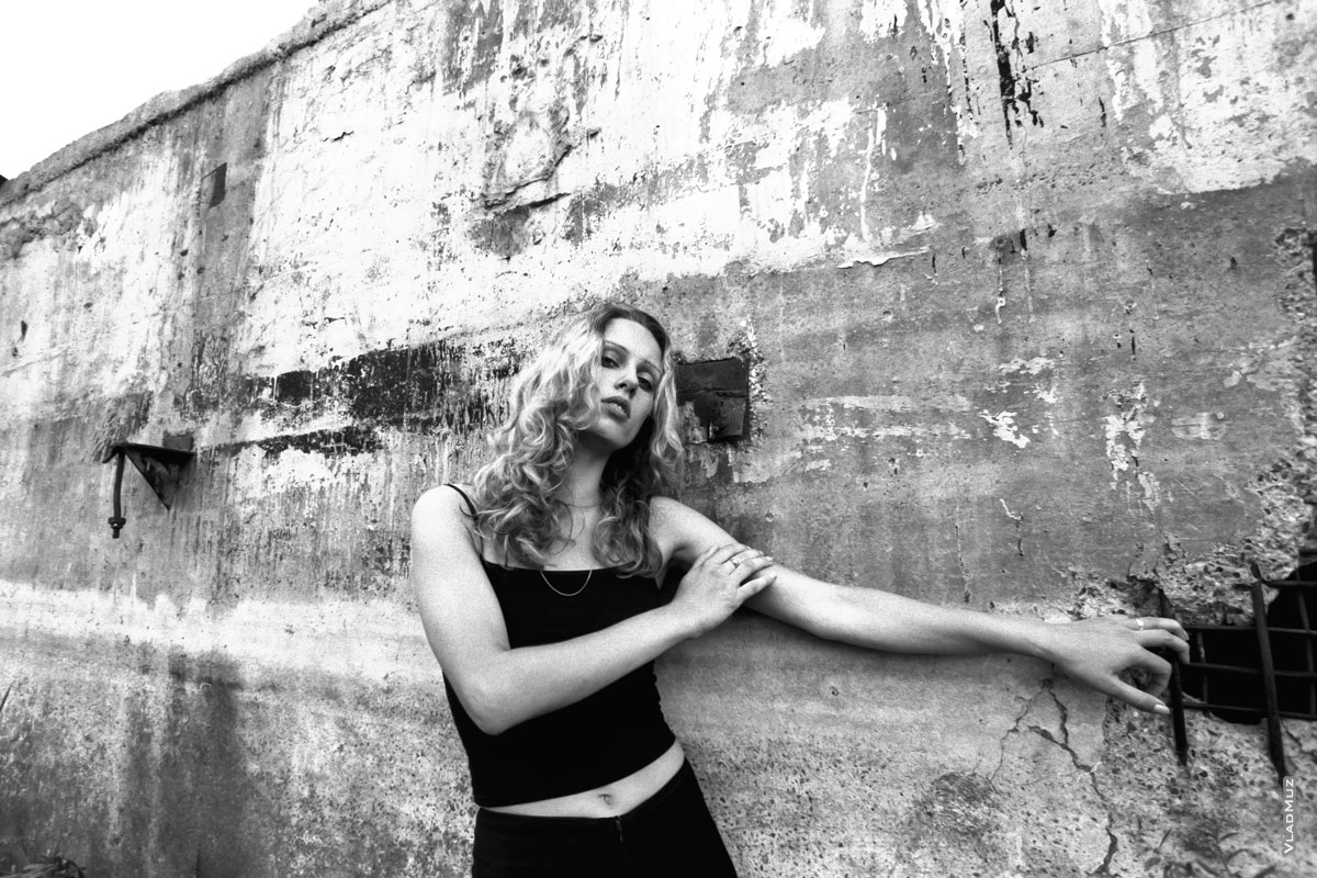 Черно-белый фотопортрет девушки у бетонной стены
