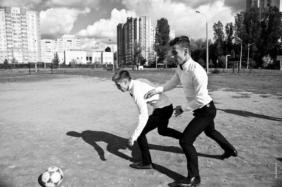 Фото двух юношей, играющих в футбол на улице