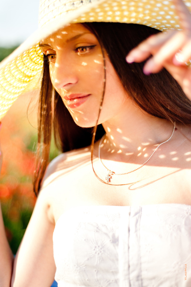 # 04 Летнее фото девушки в шляпе с солнечными бликами на лице сквозь шляпу