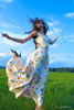 Фото девушки в поле в прыжке в длинном платье, в полный рост