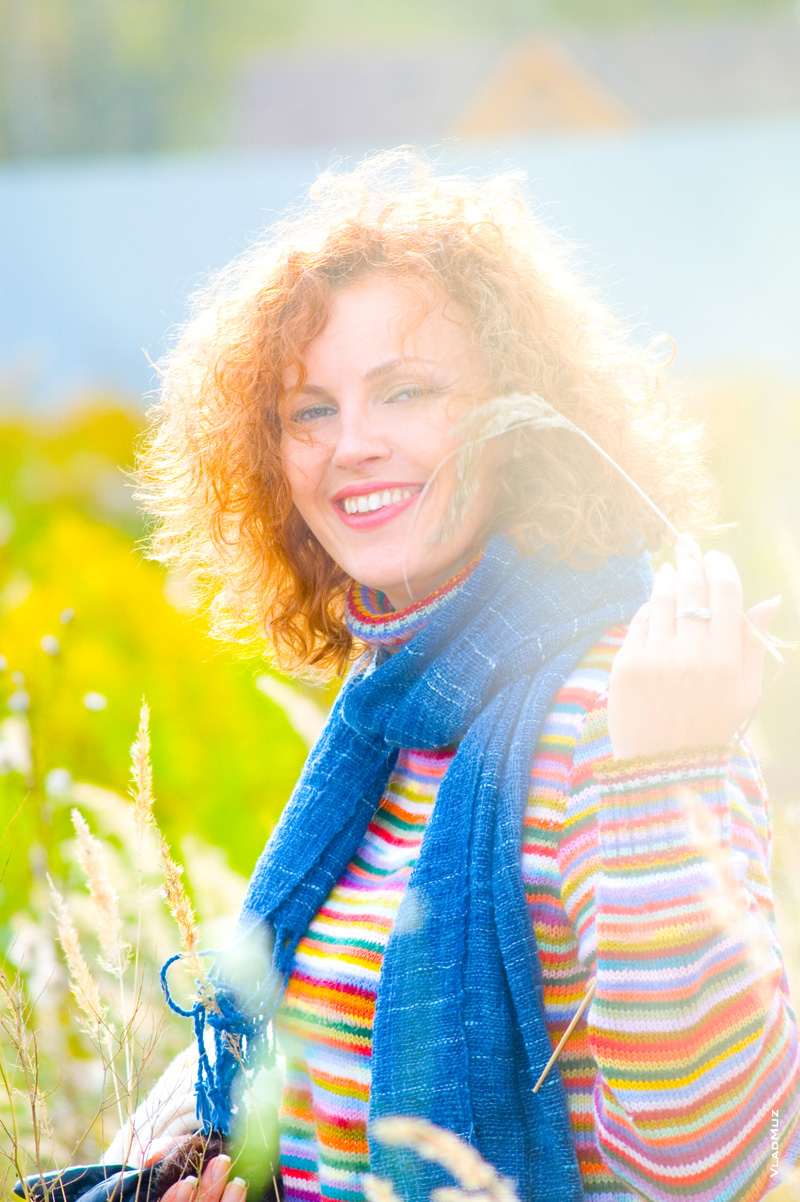 Осенний фотопортрет смеющейся девушки в ярком свитере в лучах солнца