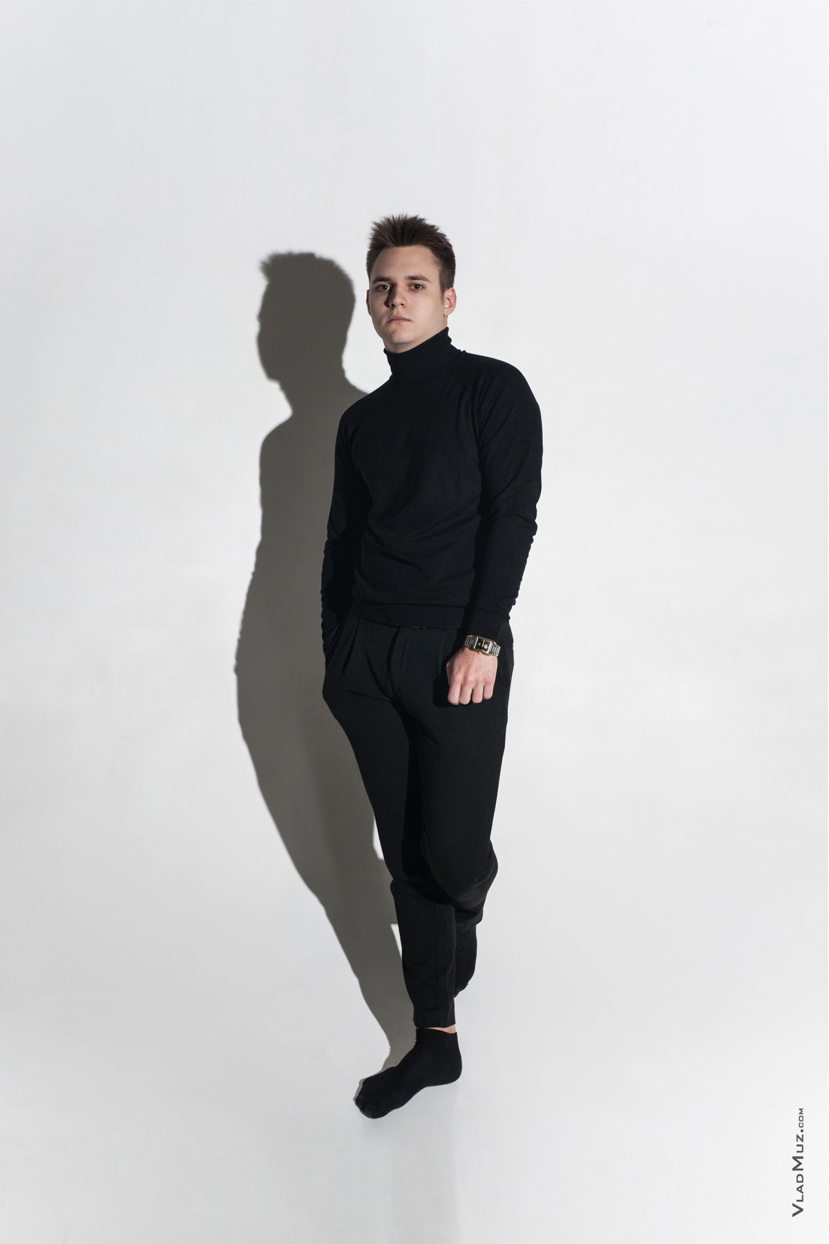 Фото мужчины-модели в студии на белой циклораме в полный рост с черной тенью на фоне